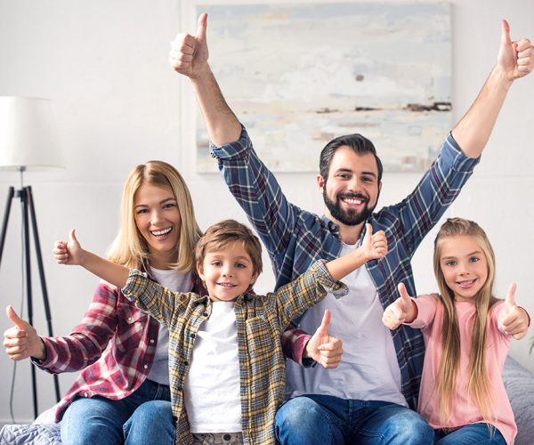 portrait of happy family showing thumbs up and looking at camera at home